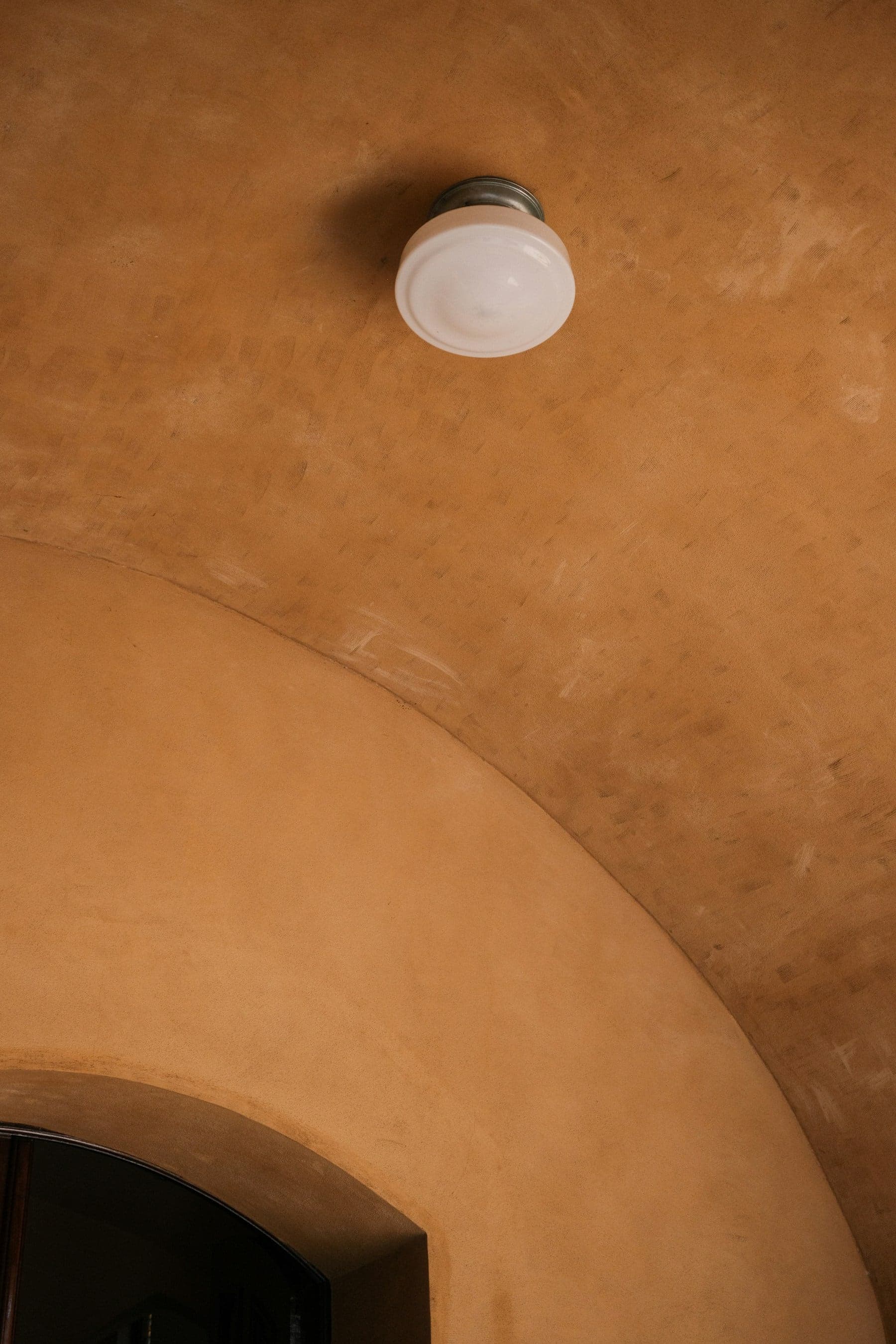 A softly vaulted ceiling finished in warm, hand-troweled lime plaster
